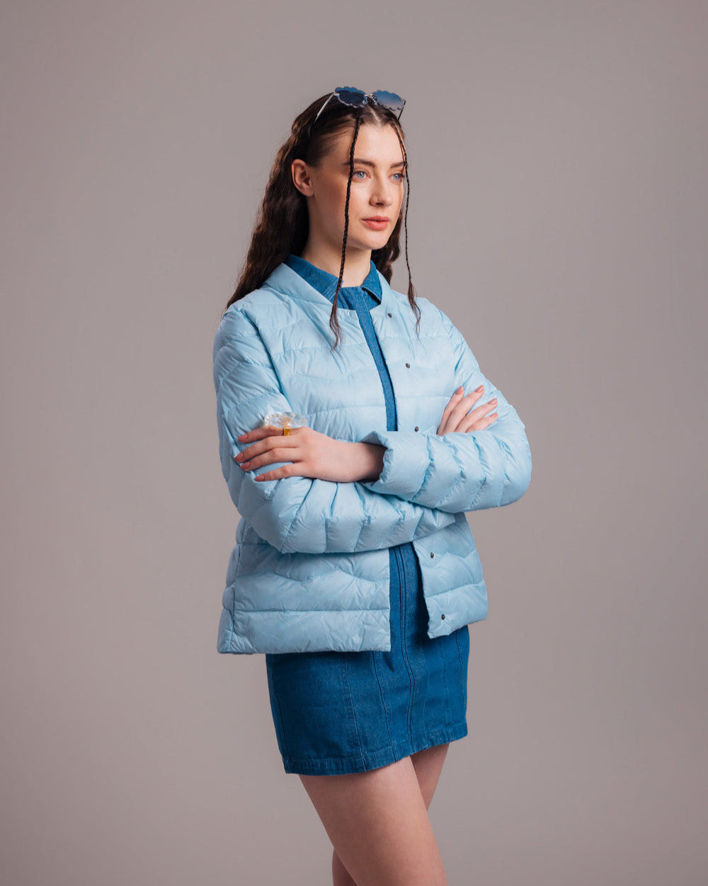 Nainen pukeutuneena vaaleansiniseen vaakatikattuun Lootus-kevytuntuvatakkiin (väri: jääkaramelli), jossa on suora malli ja pitkät hihat. Takki on yhdistetty siniseen farkkumekkoon ja aurinkolaseihin.