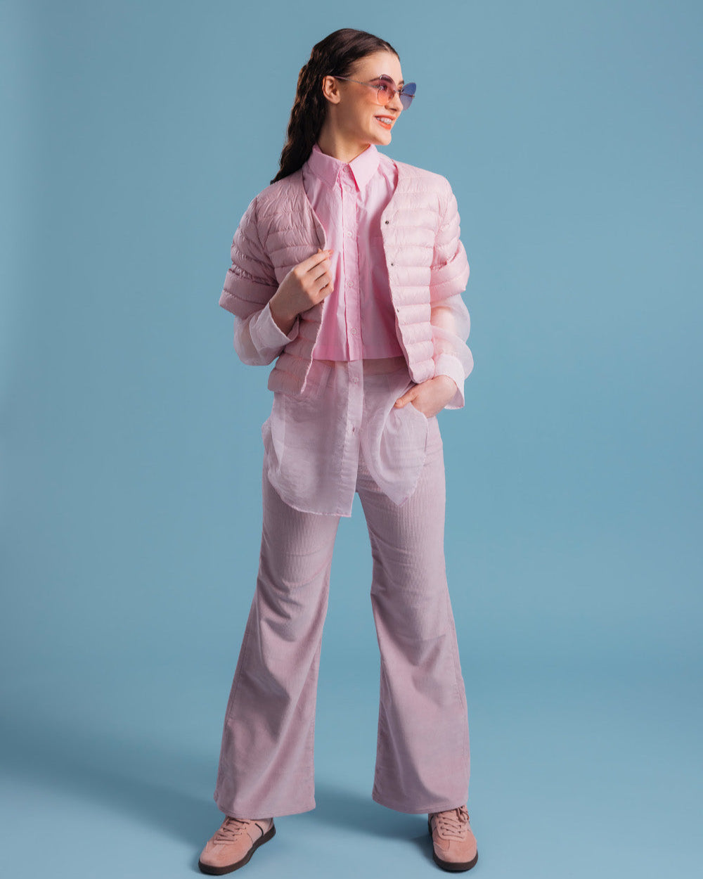 Nainen pukeutuneena vaaleanpunaiseen, vaakatikattuun, lyhyeen Lupiini-kevytuntuvatakkiin (väri: mansikkavaahto), joka on puettu pitkän kauluspaidan ja leveälahkeisten housujen päälle. Asuun kuuluu myös aurinkolasit ja vaaleanpunaiset kengät.