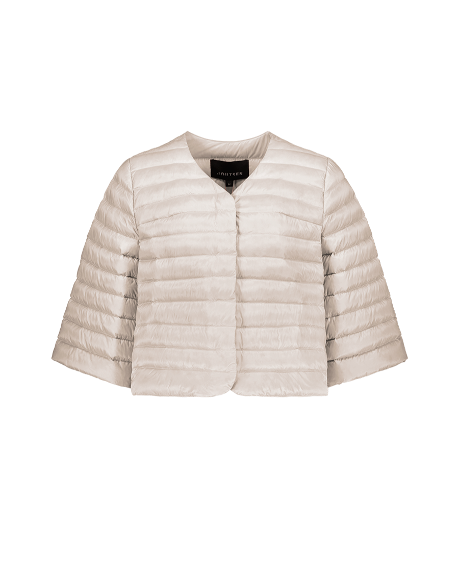 Vaalea, lyhyt ja kevyesti topattu Lupiini-kevytuntuvatakki (väri: sokeripilvi), jossa on 3/4-pituiset leveät hihat, vaakatikkaus ja pyöreä pääntie ilman kaulusta. Takissa ei ole näkyviä nappeja tai vetoketjua.