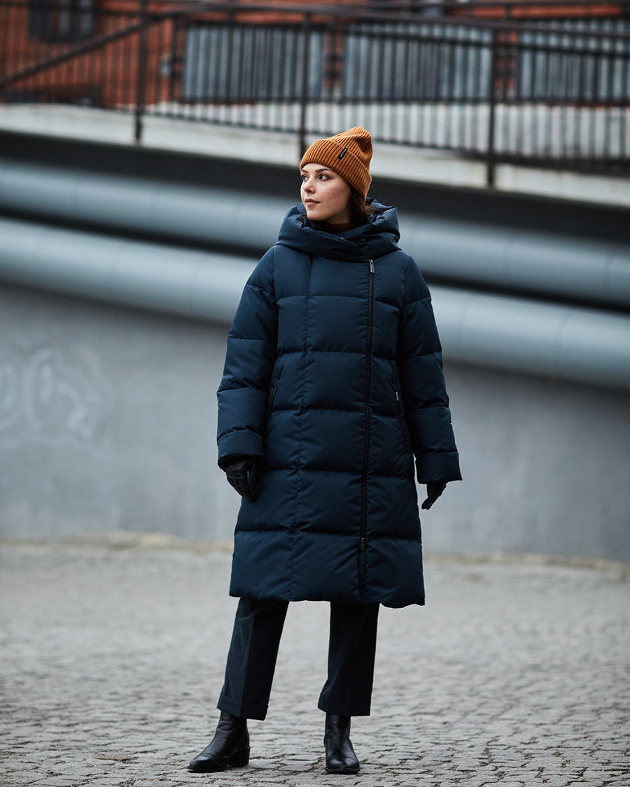 Nainen seisoo kaupunkimiljöössä pukeutuneena siniseen (väri: variksenmarjan) Lovisa-untuvatakkiin, jossa on mattapinta, leveät tikkaukset ja suuri huppu. Takin vetoketju on asetettu takin vasempaan reunaan ja se ulottuu polvien alapuolelle. Asusteina on ruskea pipo, mustat hanskat ja nilkkurit.