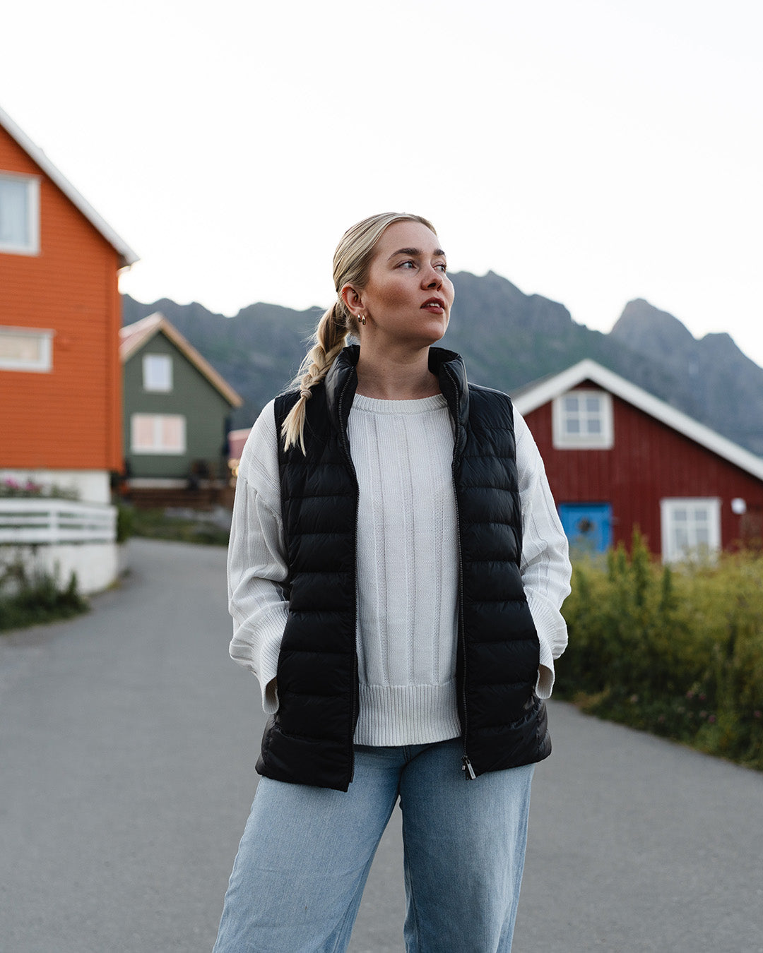 Nainen seisoo kalastajakylässä katse vasemmalle suunnattuna. Hänellä on yllään musta vaakatikattu Lady-untuvaliivi (väri: hiilenharmaa), valkoinen neule ja vaaleansiniset farkut. Liivin vetoketju on auki.